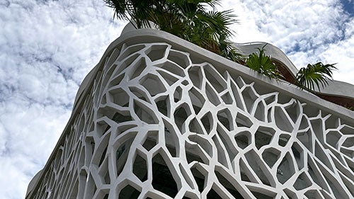 The intricate geometric concrete building facade seen at an angle from below.