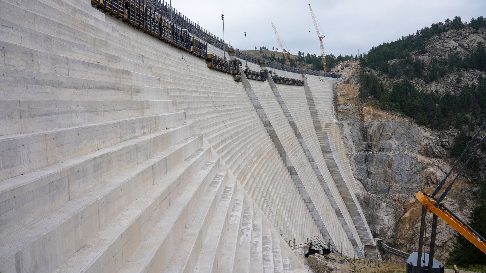 Déversoir en béton étagé massif en construction au barrage de Gross Reservoir, illustrant le projet d’expansion de 131 pieds.
