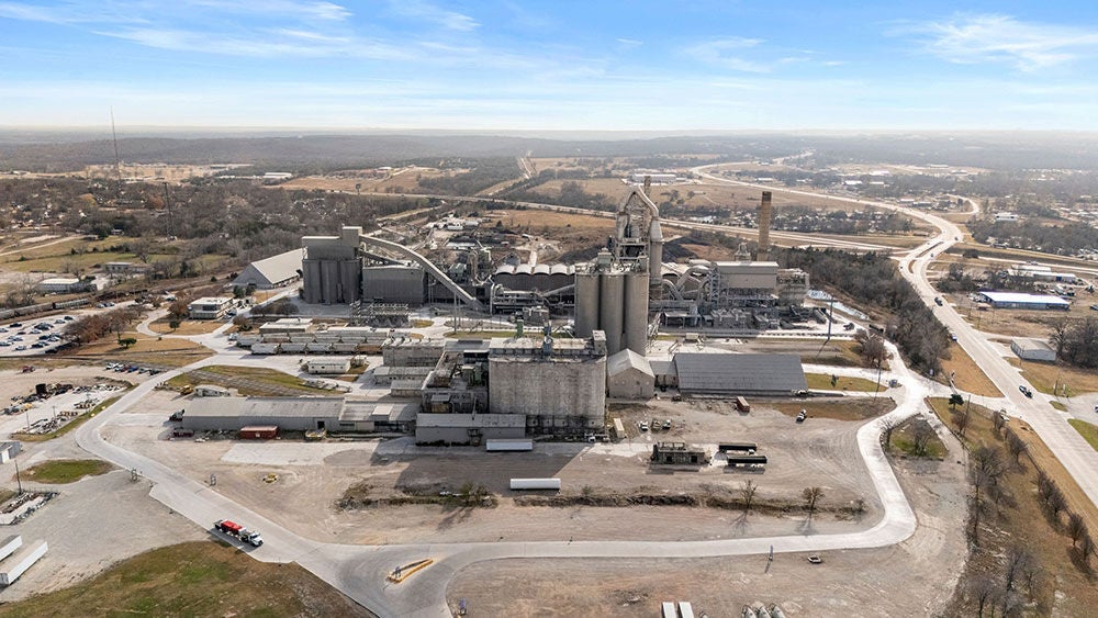 A cement plant in the middle of a green prairie at sunset