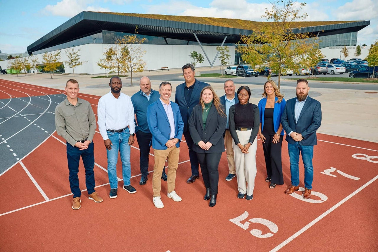 A group of men and women in business clothes standing on a running track