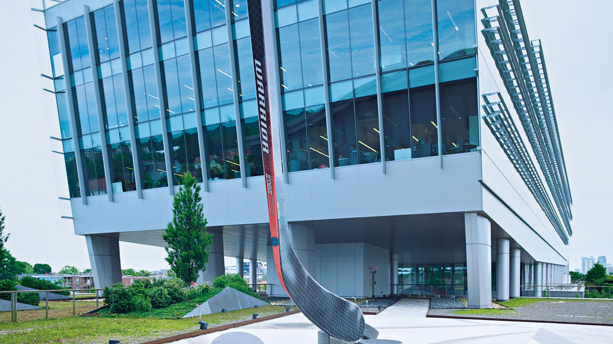 The front of a large multi-story office building with a giant hockey stick in front of it