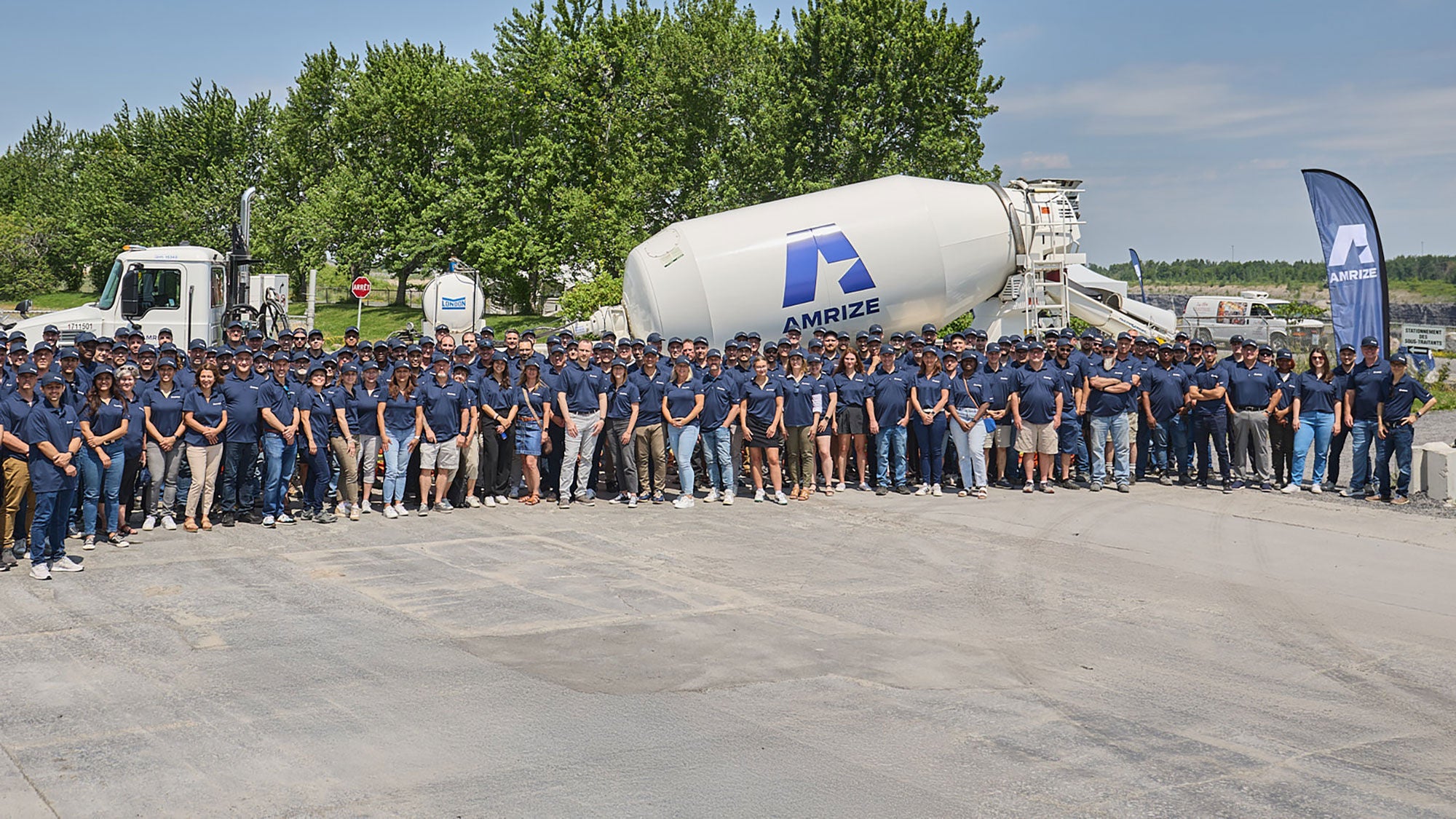 A large group of employees gather to take a team photo in front of an Amrize-branded ready-mix truck.