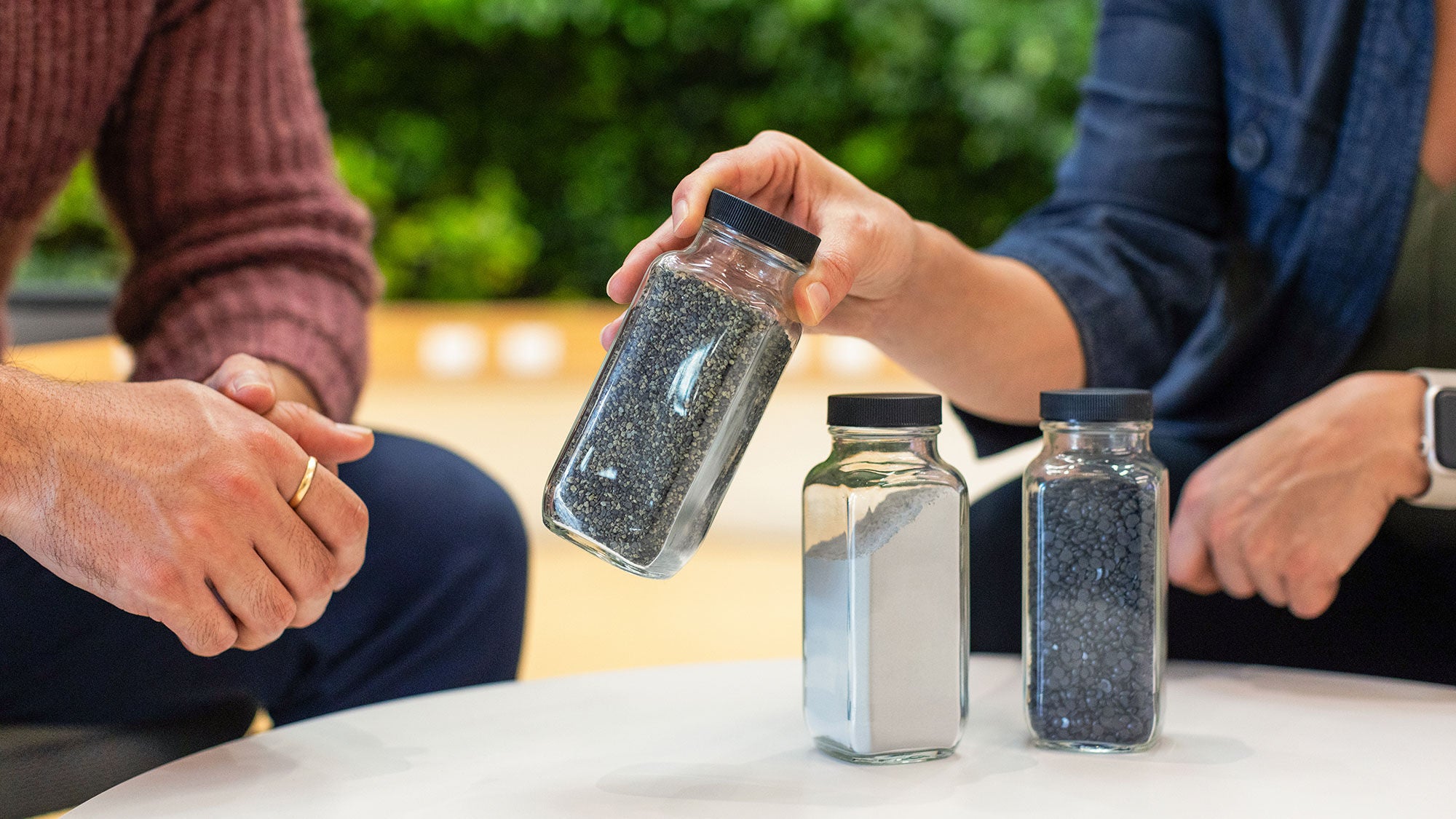 Three transparent glass containers with small particles of aggregate products sitting on a table. 
