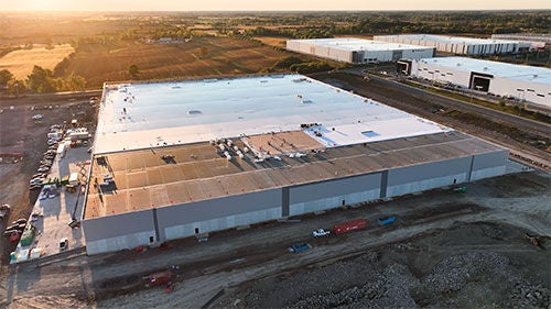 A large commercial building with a white roof half installed on it