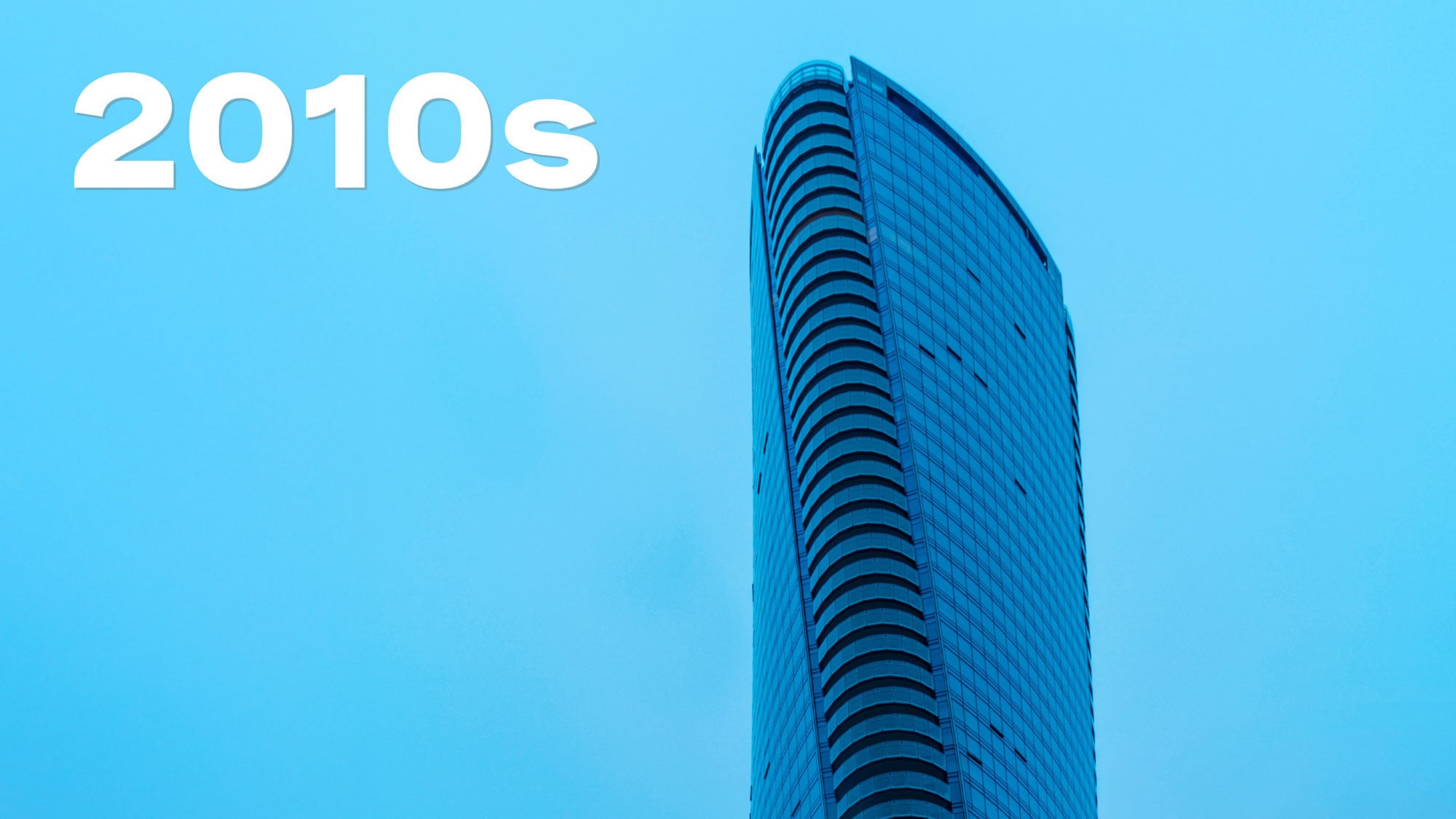 The twisting top of a modern glass and concrete skyscraper reaching into the dusk sky.