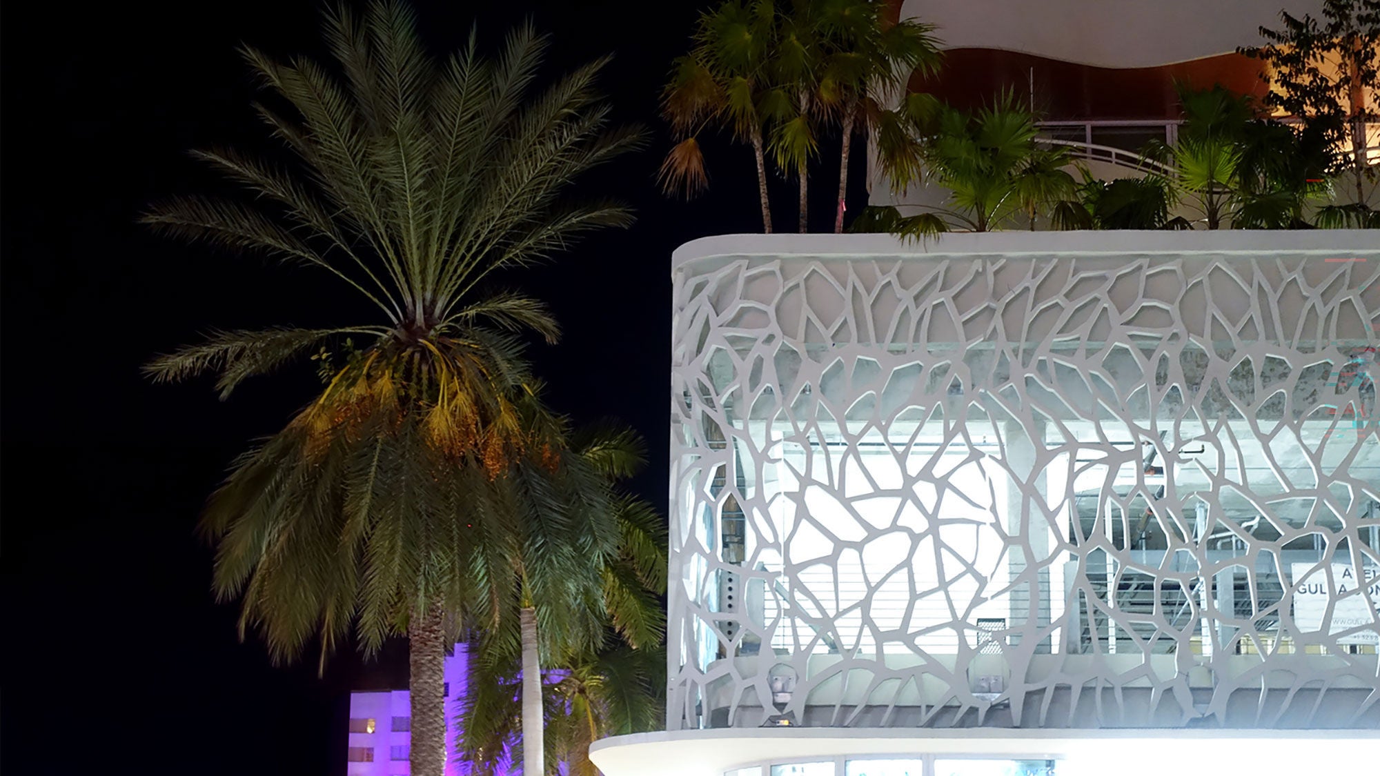 The intricate geometric concrete facade of a hotel at night time