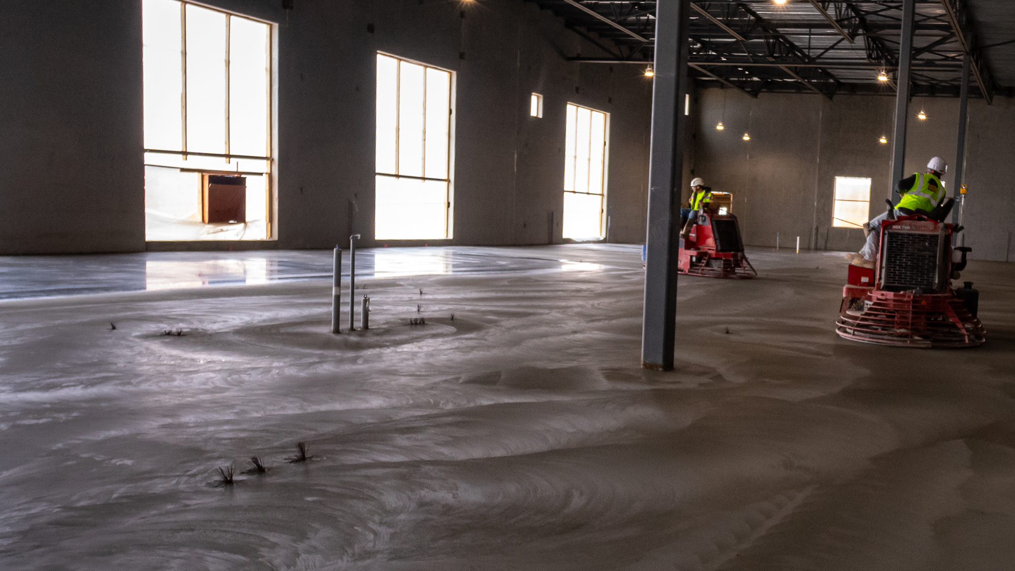 Les travailleurs utilisent des machines pour effectuer la finition du béton.