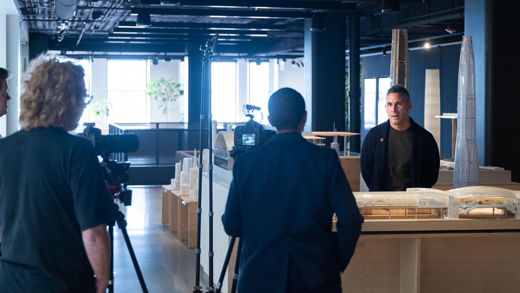 A man is interviewed among a collection of architectural models