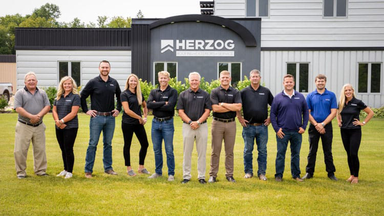 Une photo de groupe d’une équipe portant des chemises de marque Herzog Roofing