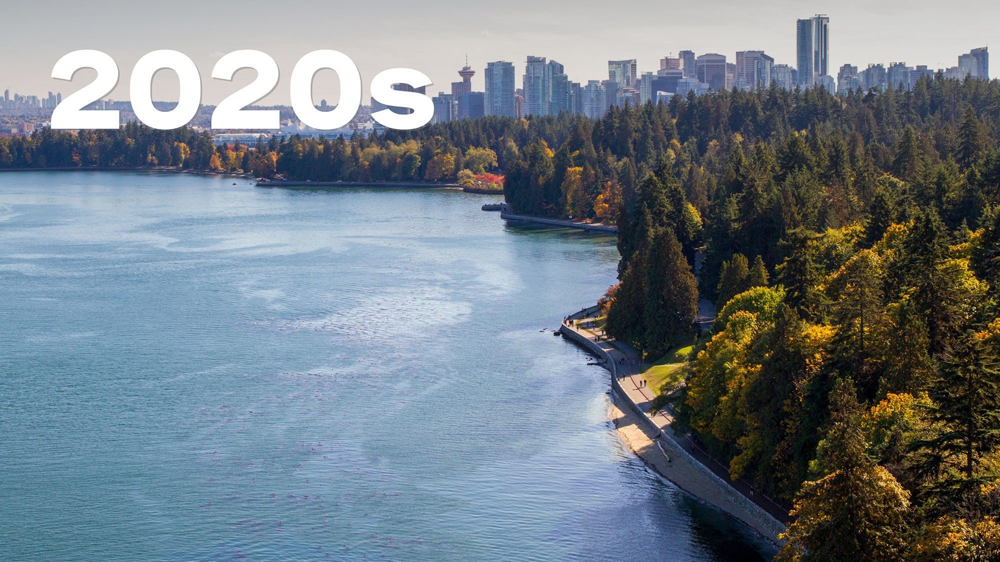 Skyline of a city, bordered by dense autumn trees and serene water. “2020s” white bold text sits above.