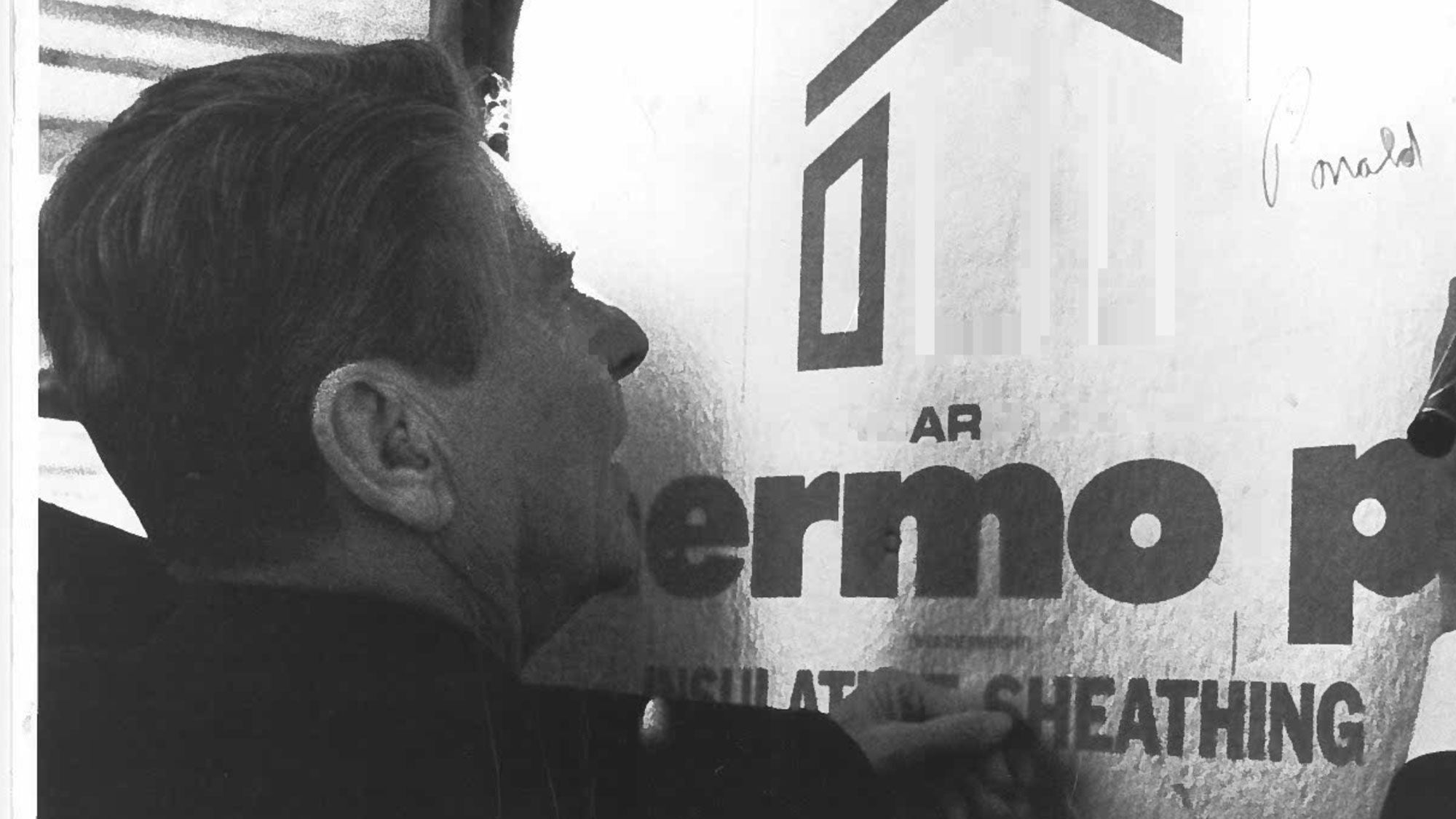 Image of President Ronald Reagan signing a piece of insulated sheathing. 