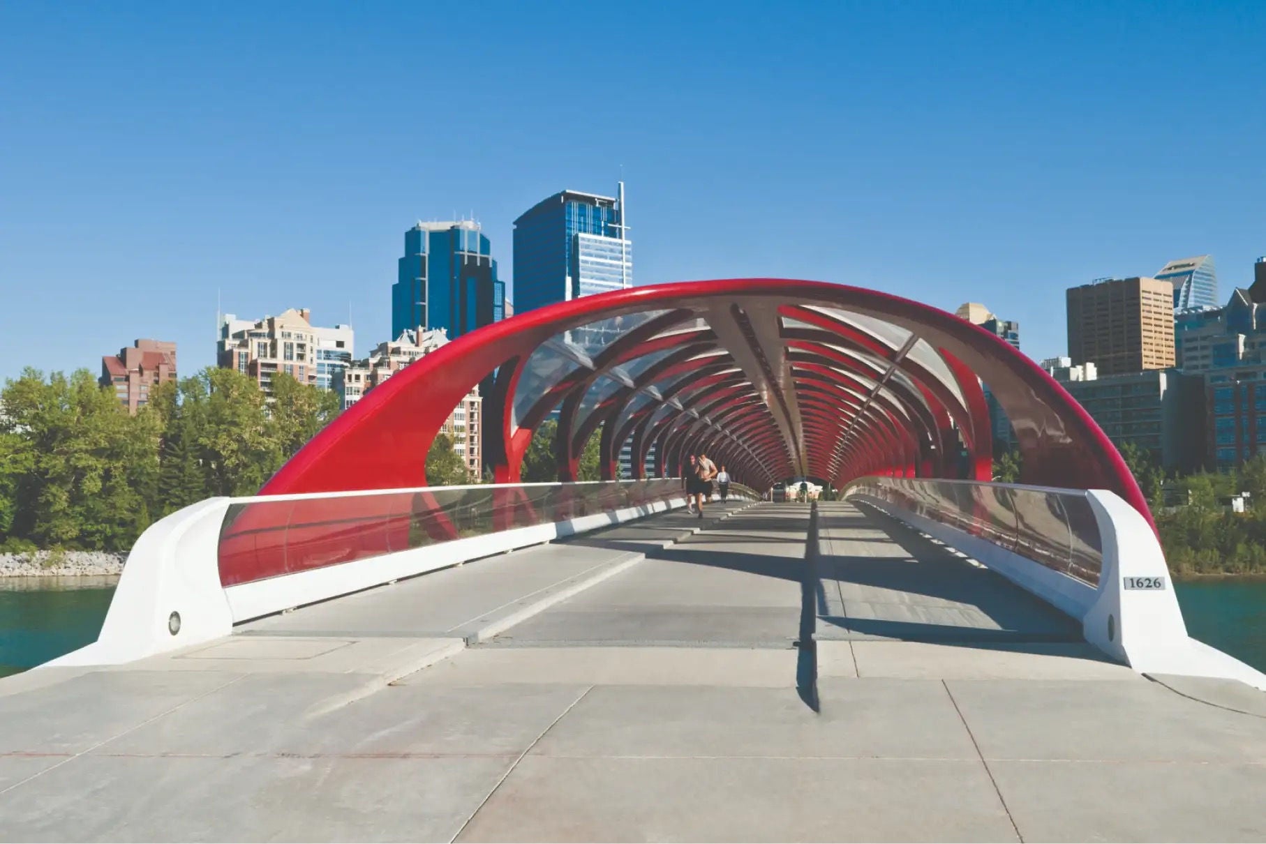 Un pont avec un toit rouge élégant, dans un environnement urbain avec des tours en arrière-plan.