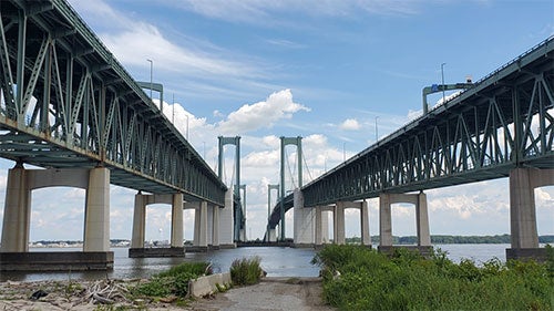 Two parallel bridges span across a river into the distance