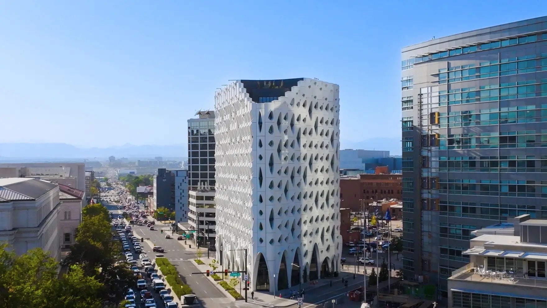 Wide shot of Populus surrounded by other downtown buildings, streets with traffic